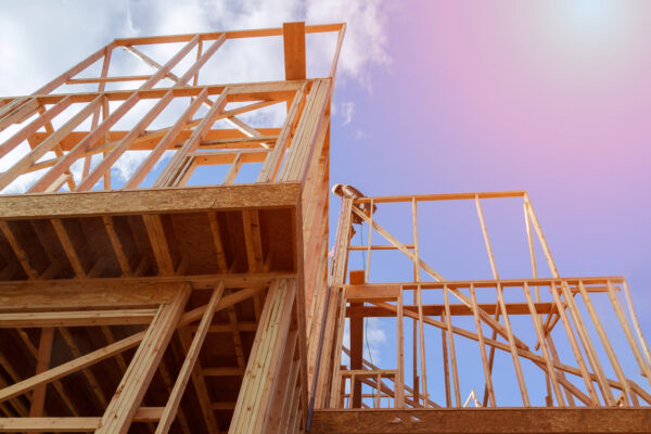 New residential construction house wood building frame against a blue sky.